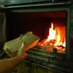 Ana O - iStock https://www.istockphoto.com/fr/photo/la-main-dun-homme-met-du-bois-dans-la-chemin%C3%A9e-allum%C3%A9e-chemin%C3%A9e-ferm%C3%A9e-moderne-avec-gm1394982585-450253843