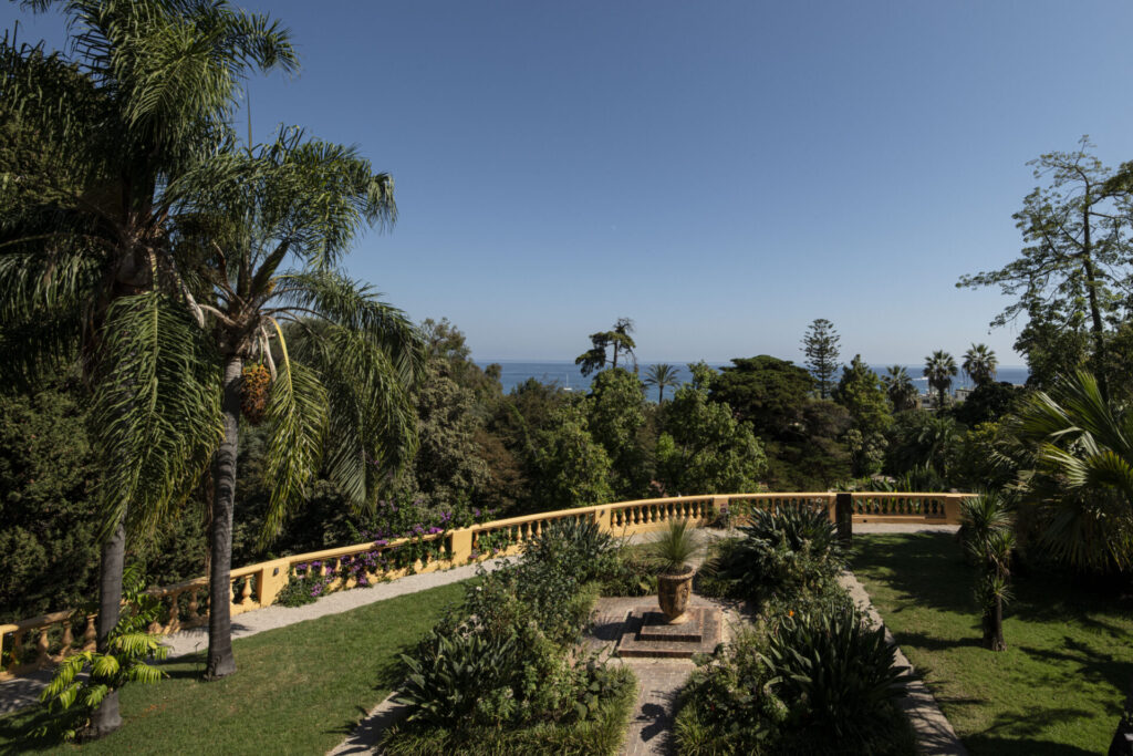 Vue sur la mer depuis le jardin de Val Rahmeh à Menton, entouré de palmiers et de plantes exotiques.