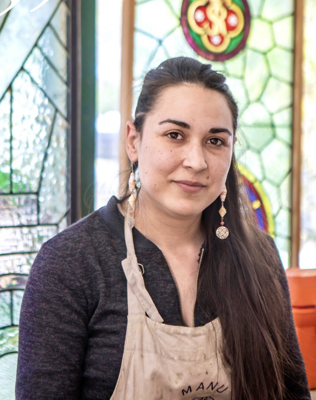 Portrait d’Emmanuelle Felzine, vitrailliste à Choisy-le-Roi, devant un vitrail coloré dans son atelier.