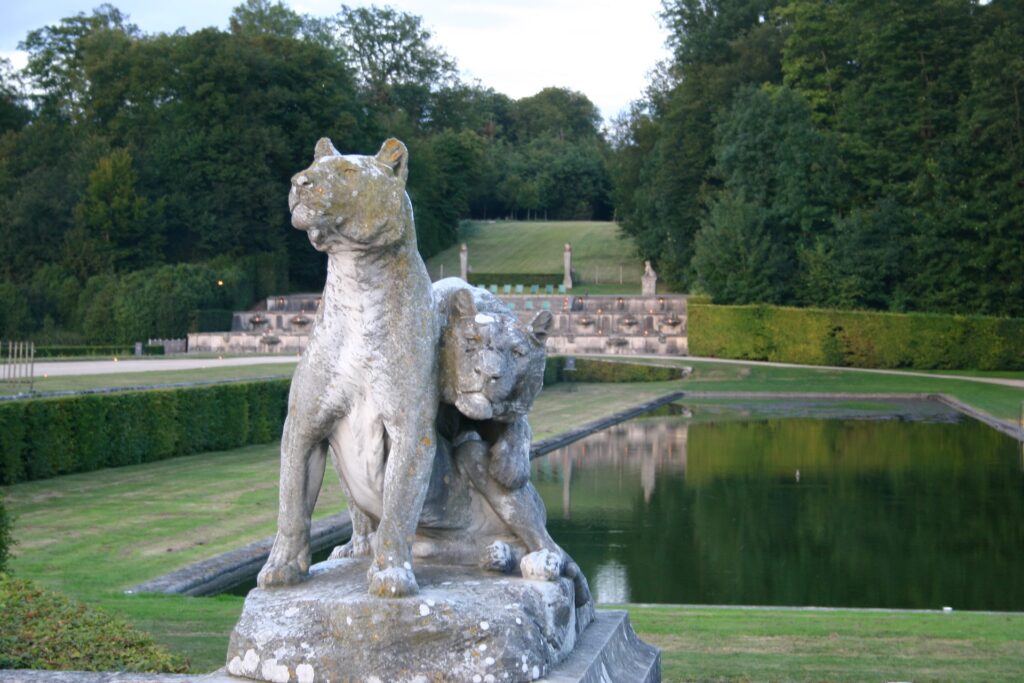 eux statues de fauves en pierre bordant un bassin dans les jardins à la française de Vaux-le-Vicomte, conçus par André Le Nôtre.