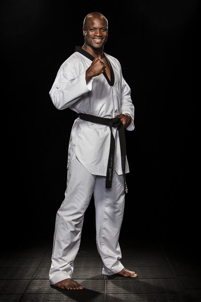 Mamédy Doucara en tenue de taekwondo, posant en studio, ceinture noire nouée à la taille.