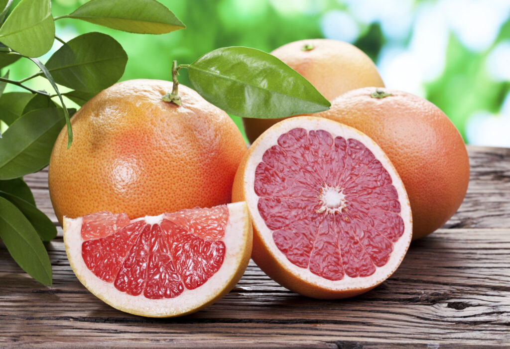 Pomelo et pamplemousse coupés montrant leur chair rosée, souvent confondus
