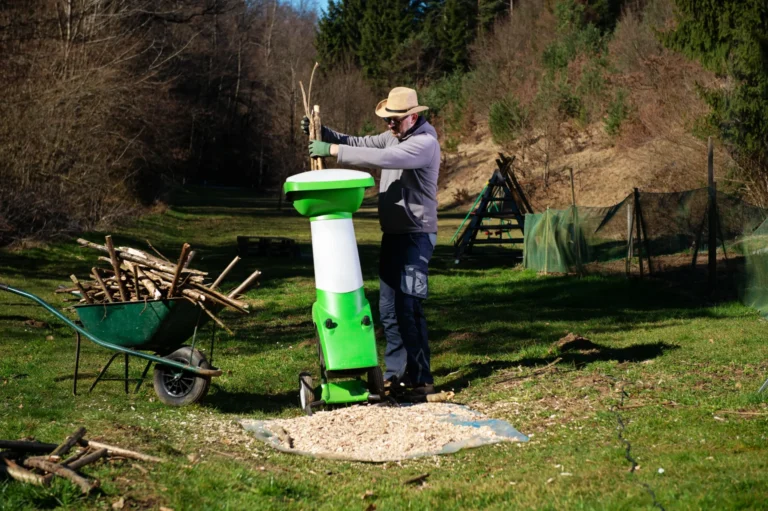 Un jardinier broie des branches avec un broyeur de végétaux