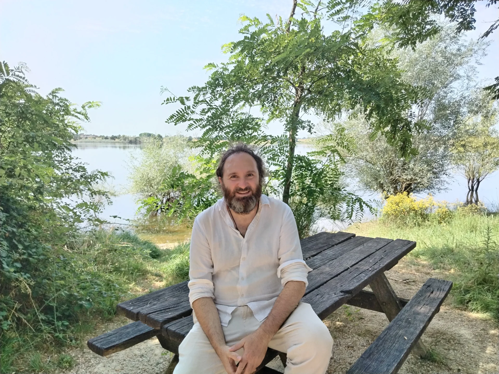 Jean-Philippe Uzan, astrophysicien au CNRS, assis sur une table de pique-nique au bord de la Seine, entouré de verdure.